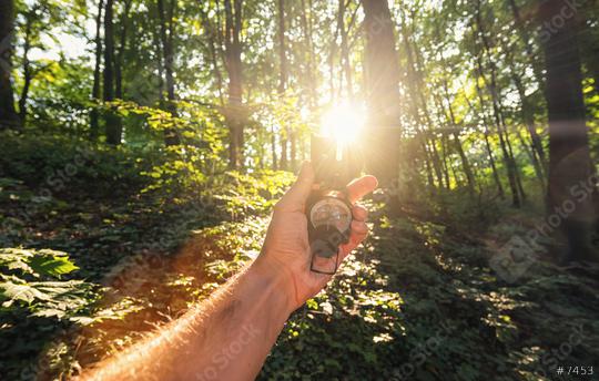 Traveler man holds a compass in the forest with explosive sunlight. Point of view shot   : Stock Photo or Stock Video Download rcfotostock photos, images and assets rcfotostock | RC Photo Stock.: