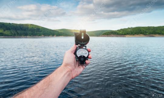 Traveler man searching direction with a compass on a coastline near a lake in the mountains. Point of view shot.  : Stock Photo or Stock Video Download rcfotostock photos, images and assets rcfotostock | RC Photo Stock.: