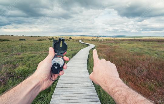 Traveler young man searching direction with a compass in the landscape with Wooden boardwalk . Point of view shot  : Stock Photo or Stock Video Download rcfotostock photos, images and assets rcfotostock | RC Photo Stock.: