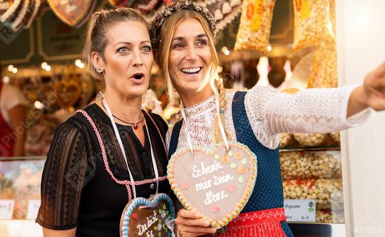 Two astonished girlfriends together on a Bavarian fair or oktoberfest or duld in national costume or Dirndl with Schenk mir dein Herz (German: Give me your heart) written on gingerbreads heart  : Stock Photo or Stock Video Download rcfotostock photos, images and assets rcfotostock | RC Photo Stock.: