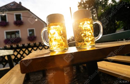 Two bavarian beer mugs on wooden table, backlight by sun at beer garden or at Oktoberfest, Munich, Germany  : Stock Photo or Stock Video Download rcfotostock photos, images and assets rcfotostock | RC Photo Stock.: