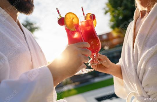 Two people in white bathrobes toasting with red cocktails in the sunlight, outdoors at spa wellness hotel  : Stock Photo or Stock Video Download rcfotostock photos, images and assets rcfotostock | RC Photo Stock.: