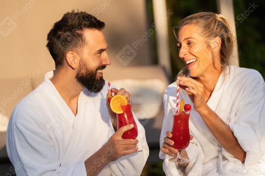 Two people in white robes laughing and drinking cocktails in the sunlight at a wellness hotel  : Stock Photo or Stock Video Download rcfotostock photos, images and assets rcfotostock | RC Photo Stock.: