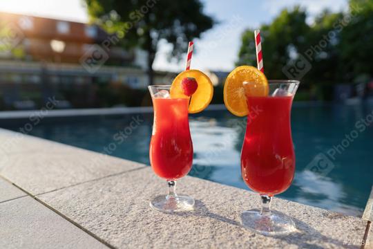 Two red cocktails with fruit garnishes by a poolside, reflecting the warm sunset light  : Stock Photo or Stock Video Download rcfotostock photos, images and assets rcfotostock | RC Photo Stock.: