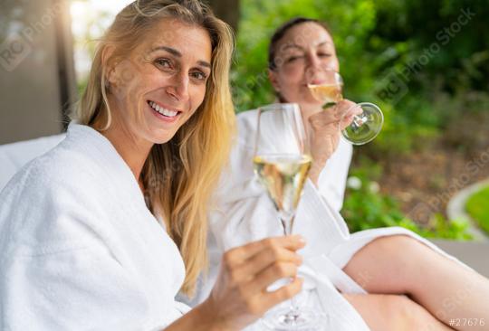 Two smiling women in white bathrobes enjoying champagne outdoors on a lounger at a spa resort  : Stock Photo or Stock Video Download rcfotostock photos, images and assets rcfotostock | RC Photo Stock.: