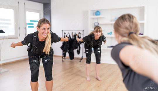 Two women in EMS training suits doing balance exercises front of a trainer in a gym  : Stock Photo or Stock Video Download rcfotostock photos, images and assets rcfotostock | RC Photo Stock.: