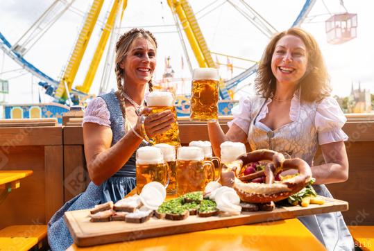 Two women in traditional Bavarian dresses or tracht toasting with beer mugs and  beer and snacks on the table at a festive fairground in Bavaria oktoberfest or dult  : Stock Photo or Stock Video Download rcfotostock photos, images and assets rcfotostock | RC Photo Stock.: