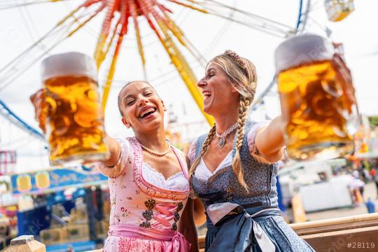 Two women in vibrant Bavarian dresses tracht joyfully toasting with large beer mugs at oktoberfest or duld in germany  : Stock Photo or Stock Video Download rcfotostock photos, images and assets rcfotostock | RC Photo Stock.: