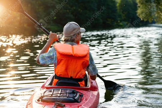 view from behind of a woman in an orange life vest paddling a red kayak on a river, sunlit trees in the background at summer in germany. Kayak Water Sports concept image  : Stock Photo or Stock Video Download rcfotostock photos, images and assets rcfotostock | RC Photo Stock.: