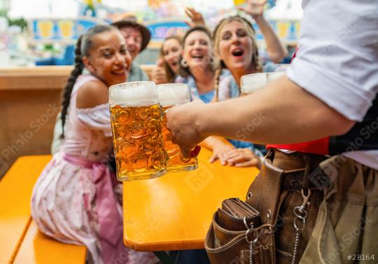 Waiter serving beer to a joyful group of friends at oktoberfest festival or duld in munich, amusement rides in the background  : Stock Photo or Stock Video Download rcfotostock photos, images and assets rcfotostock | RC Photo Stock.: