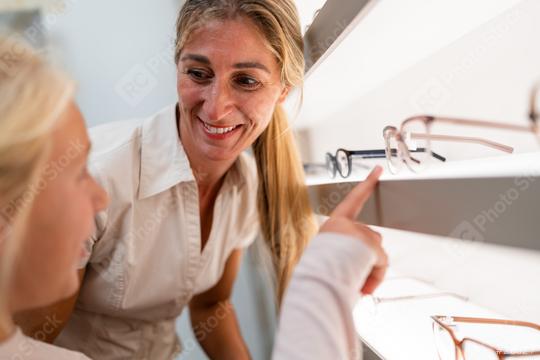 Woman and child looking at new glasses in an optical store. Daughter points to her favorite glasses.  : Stock Photo or Stock Video Download rcfotostock photos, images and assets rcfotostock | RC Photo Stock.: