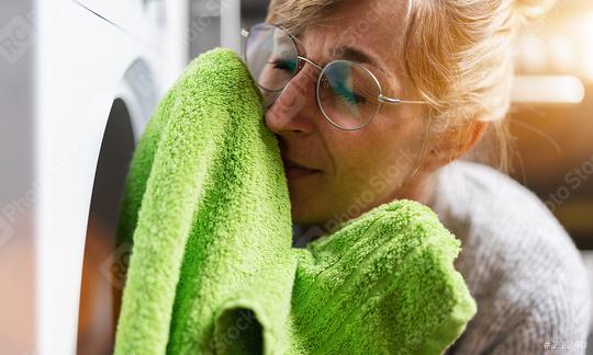 Woman at housework smells at fresh clothes from the clothes dryer  : Stock Photo or Stock Video Download rcfotostock photos, images and assets rcfotostock | RC Photo Stock.: