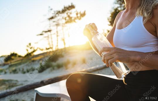 woman athlete takes a break at the beach forest, holding water bottle at sunset on a hot day.  : Stock Photo or Stock Video Download rcfotostock photos, images and assets rcfotostock | RC Photo Stock.: