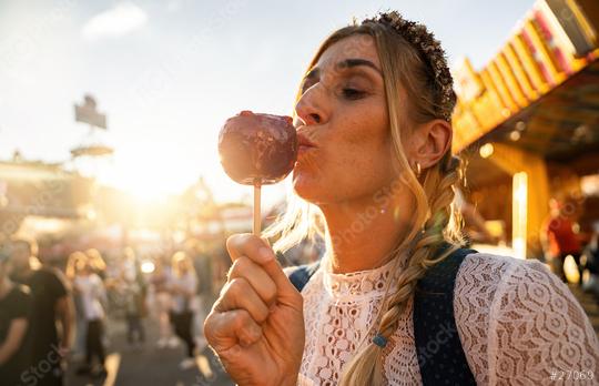 Woman eating candy apple at Oktoberfest wearing Dirndl in germany   : Stock Photo or Stock Video Download rcfotostock photos, images and assets rcfotostock | RC Photo Stock.: