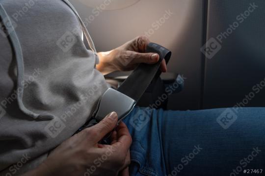 Woman fastening seat belt on a commercial airplane, close-up on buckle and hand. safe flight on airplane concept image  : Stock Photo or Stock Video Download rcfotostock photos, images and assets rcfotostock | RC Photo Stock.: