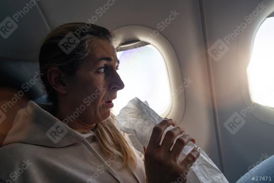 woman flying in airplane and  holding a sick bag looking out the window and breathing into paper bag  : Stock Photo or Stock Video Download rcfotostock photos, images and assets rcfotostock | RC Photo Stock.: