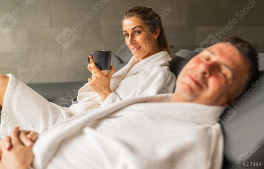 Woman holding mug of hot tea and smiling, man with closed eyes relaxing in spa  : Stock Photo or Stock Video Download rcfotostock photos, images and assets rcfotostock | RC Photo Stock.: