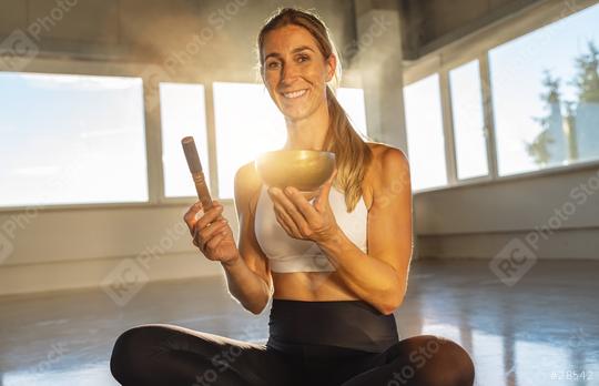 Woman holding singing bowl and mallet in gym, sunlit, peaceful meditation  : Stock Photo or Stock Video Download rcfotostock photos, images and assets rcfotostock | RC Photo Stock.: