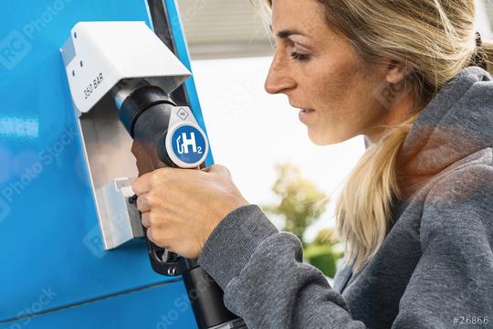 woman holds a fuel dispenser with hydrogen logo on gas station to fill up her car. h2 combustion engine for emission free eco friendly transport concept image  : Stock Photo or Stock Video Download rcfotostock photos, images and assets rcfotostock | RC Photo Stock.: