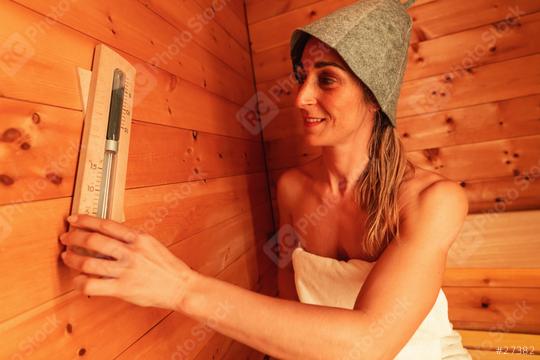 Woman in a sauna wearing a felt hat, smiling while adjusting a wall-mounted thermometer  : Stock Photo or Stock Video Download rcfotostock photos, images and assets rcfotostock | RC Photo Stock.: