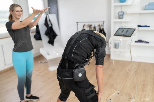 Woman in EMS suit performing exercises with trainer guidance and computer in a EMS - Studio  : Stock Photo or Stock Video Download rcfotostock photos, images and assets rcfotostock | RC Photo Stock.: