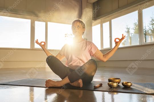 Woman in meditation pose with singing bowls, serene gym atmosphere, sun flare  : Stock Photo or Stock Video Download rcfotostock photos, images and assets rcfotostock | RC Photo Stock.: