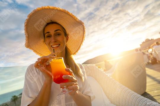 Woman in straw hat sipping a tropical cocktail at tropical beach hotel on sunset with a blurred background  : Stock Photo or Stock Video Download rcfotostock photos, images and assets rcfotostock | RC Photo Stock.: