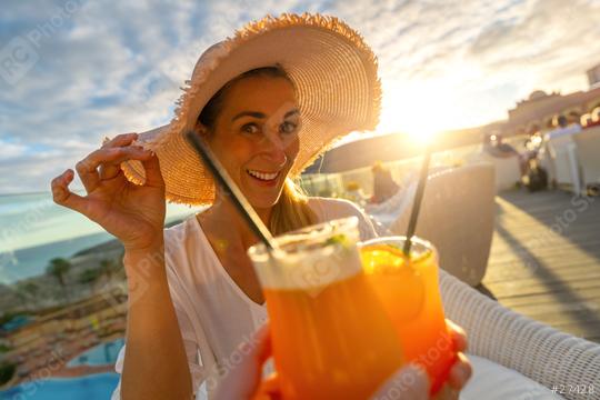 Woman in sun hat smiling and toasting with a cocktail at tropical beach hotel on sunset with blurry background  : Stock Photo or Stock Video Download rcfotostock photos, images and assets rcfotostock | RC Photo Stock.: