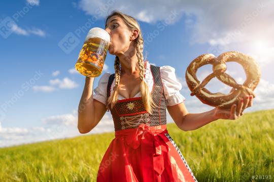 Woman in traditional Bavarian tracht enjoying a beer and pretzel in a sunny wheat field celebrating Oktoberfest festival in munich.  : Stock Photo or Stock Video Download rcfotostock photos, images and assets rcfotostock | RC Photo Stock.: