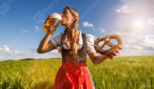 Woman in traditional Bavarian tracht enjoying a beer and pretzel in a sunny wheat field celebrating Oktoberfest festival in munich.  : Stock Photo or Stock Video Download rcfotostock photos, images and assets rcfotostock | RC Photo Stock.: