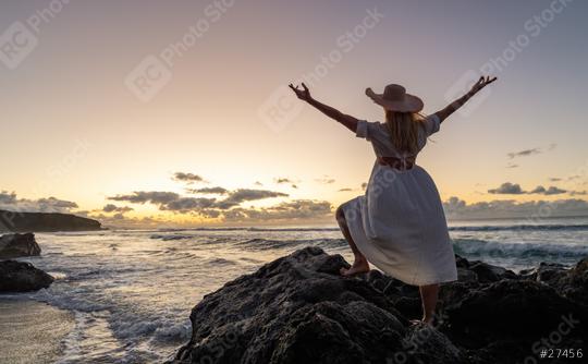 Woman in white dress and straw hat, arms raised, celebrating on rocky beach at sunset with ocean waves  : Stock Photo or Stock Video Download rcfotostock photos, images and assets rcfotostock | RC Photo Stock.: