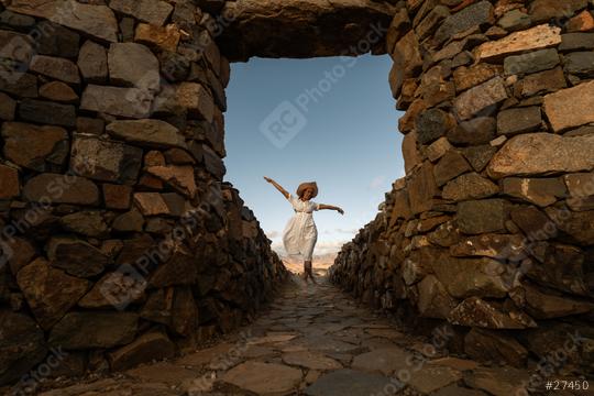 Woman in white dress and straw hat jumping joyfully in a stone archway at fuerteventura   : Stock Photo or Stock Video Download rcfotostock photos, images and assets rcfotostock | RC Photo Stock.: