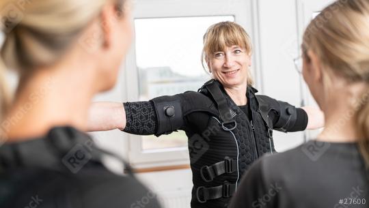 woman is being assisted with fitting an EMS training suit by a trainer in a modern EMS-Studio  : Stock Photo or Stock Video Download rcfotostock photos, images and assets rcfotostock | RC Photo Stock.: