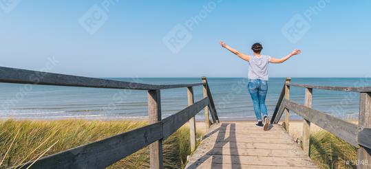 woman is raising hands on a wooden path to the Baltic sea over sand dunes  : Stock Photo or Stock Video Download rcfotostock photos, images and assets rcfotostock | RC Photo Stock.: