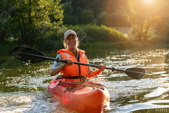 Woman joyfully paddling a red kayak in a river during sunset, surrounded by lush greenery. Kayak Water Sports concept image  : Stock Photo or Stock Video Download rcfotostock photos, images and assets rcfotostock | RC Photo Stock.: