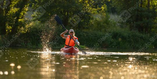 Woman kayaking in calm river waters at sunset, creating a splash with his paddle wearing an orange life jacket at summer. Kayak Water Sports concept image  : Stock Photo or Stock Video Download rcfotostock photos, images and assets rcfotostock | RC Photo Stock.: