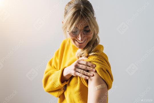 Woman looking happy after getting Covid 19 vaccine shot. Caucasian woman with bandage on her arm after receiving vaccination looking down and smile.  : Stock Photo or Stock Video Download rcfotostock photos, images and assets rcfotostock | RC Photo Stock.: