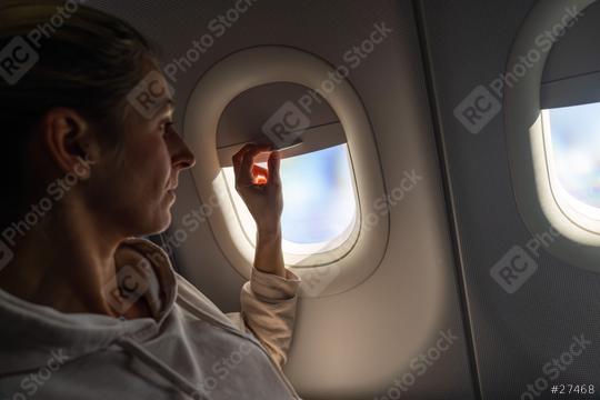 Woman on airplane looking out and a adjusting the sunshade the window on a airplane, sunlight streaming through  : Stock Photo or Stock Video Download rcfotostock photos, images and assets rcfotostock | RC Photo Stock.: