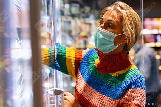 Woman shopping in supermarket takes something out of the fresh food cabinet during coronavirus lockdown at freezer section   : Stock Photo or Stock Video Download rcfotostock photos, images and assets rcfotostock | RC Photo Stock.: