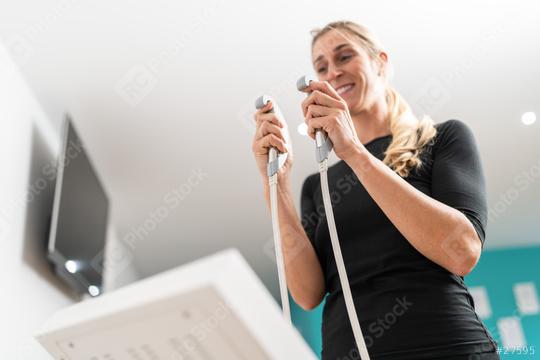 Woman smiling and holding grips of a body composition monitor for Inbody test in a fitness center, with a blurred background.  : Stock Photo or Stock Video Download rcfotostock photos, images and assets rcfotostock | RC Photo Stock.: