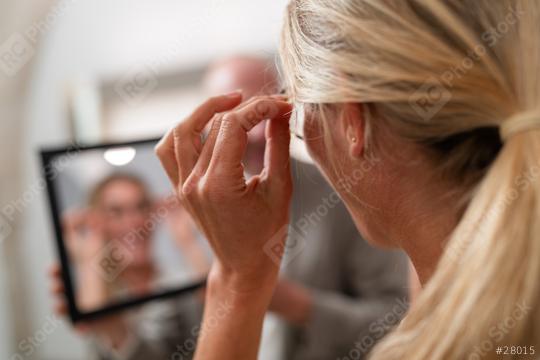 Woman trying on glasses and looking at her reflection in a mirror on a optician store. The focus is on hands holding glasses with blurred background  : Stock Photo or Stock Video Download rcfotostock photos, images and assets rcfotostock | RC Photo Stock.: