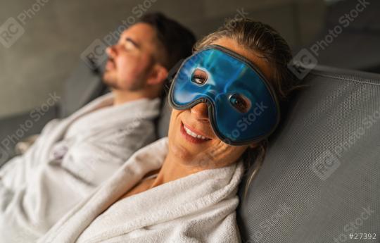 Woman wearing blue gel eye mask smiling, man in background relaxing in spa hotel  : Stock Photo or Stock Video Download rcfotostock photos, images and assets rcfotostock | RC Photo Stock.: