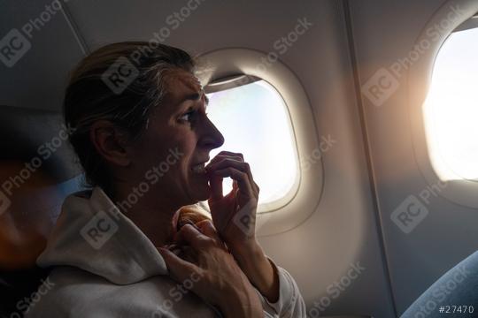 Woman with aerophobia in airplane cabin is afraid to fly on an airplane and nibbling on fingers, looking out the window  : Stock Photo or Stock Video Download rcfotostock photos, images and assets rcfotostock | RC Photo Stock.: