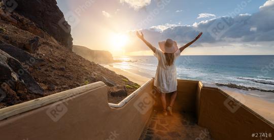 Woman with arms outstretched at the beach stairs enjoying the sunset over the ocean at Playa de Cofete, Fuerteventura, Canary Islands.  : Stock Photo or Stock Video Download rcfotostock photos, images and assets rcfotostock | RC Photo Stock.: