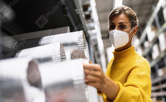 woman with face mask examines silver ventilation tubes in a warehouse or store setting.  Corona safety Concept image  : Stock Photo or Stock Video Download rcfotostock photos, images and assets rcfotostock | RC Photo Stock.: