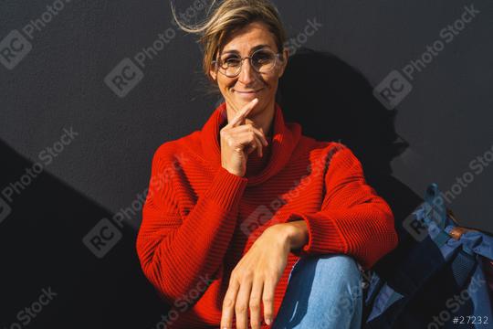 woman with red sweater sitting against a black wall, holding her hand to her chin and looking amazed. University concept image.  : Stock Photo or Stock Video Download rcfotostock photos, images and assets rcfotostock | RC Photo Stock.: