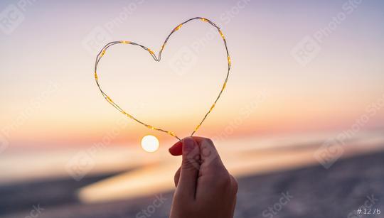 womand holding Heart shape made of led lights at the beach on sunset  : Stock Photo or Stock Video Download rcfotostock photos, images and assets rcfotostock | RC Photo Stock.: