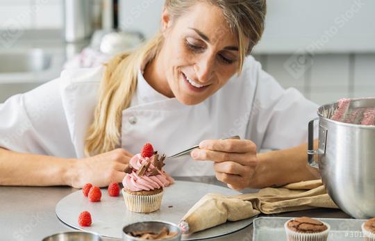 women in pastry bakery as confectioner draped pieces of chocolate on a muffin topping with tweezers  : Stock Photo or Stock Video Download rcfotostock photos, images and assets rcfotostock | RC Photo Stock.: