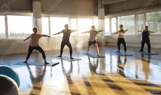 Yoga class practicing warrior pose, sunlit studio with reflective flooring  : Stock Photo or Stock Video Download rcfotostock photos, images and assets rcfotostock | RC Photo Stock.: