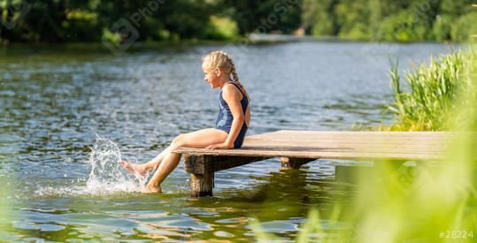 Young girl seated on a wooden dock, splashing water with her feet in a lake on a sunny day at summer in germany  : Stock Photo or Stock Video Download rcfotostock photos, images and assets rcfotostock | RC Photo Stock.: